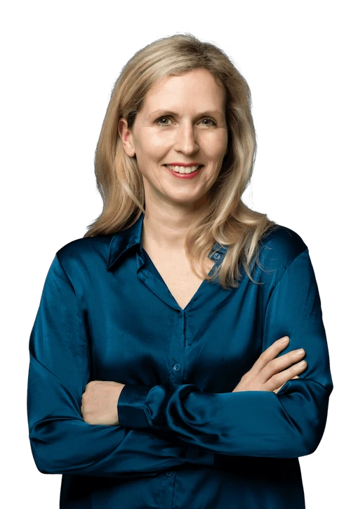 Porträt von Dr. med. Sina Bloching, freundlich lächelnd, mit verschränkten Armen in einer glänzenden petrolfarbenen Bluse, vor transparentem Hintergrund. Das Bild ist auf der Teamsektion verankert